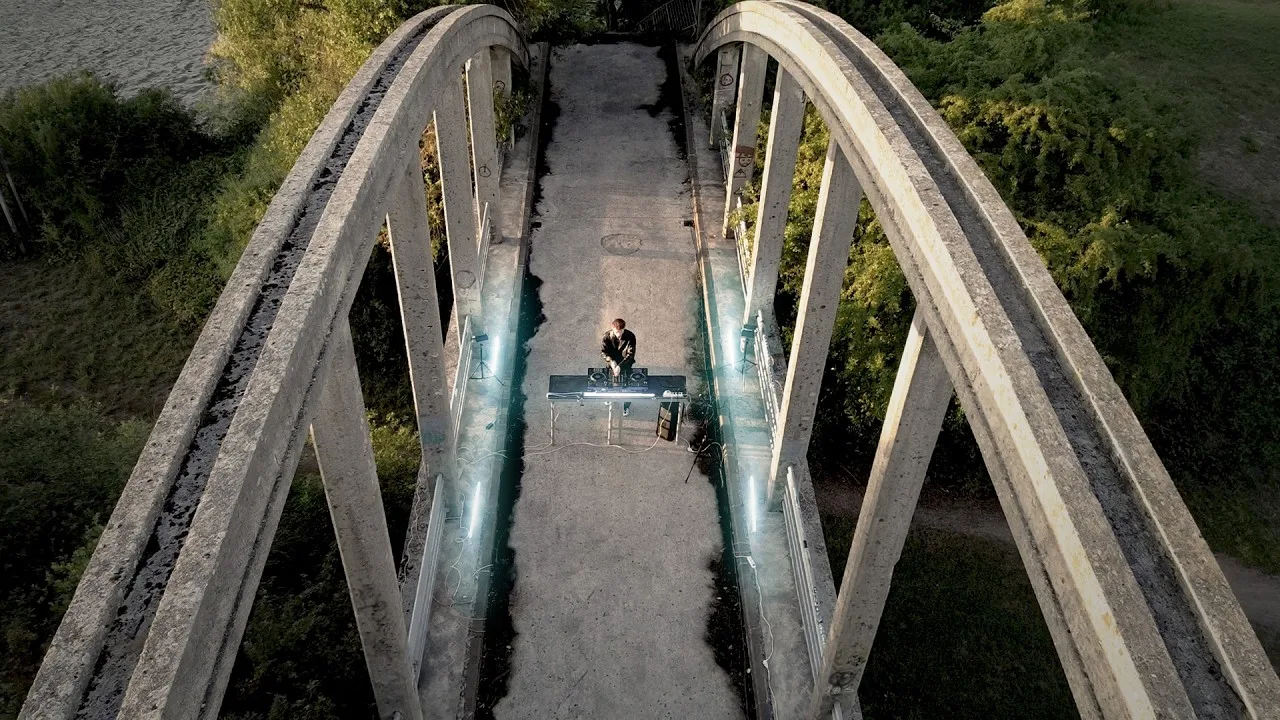 Yann Vertige mixe au milieu d’un pont en béton, vu du ciel
